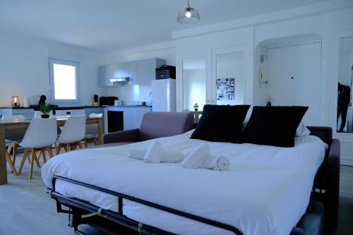 a bedroom with a large white bed and a kitchen at CALYPSO- Grand T3 - Arrivée Autonome - Parking & Wifi gratuit in Melun