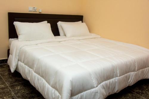 a large white bed with white sheets and pillows at High Level Apartment in Accra