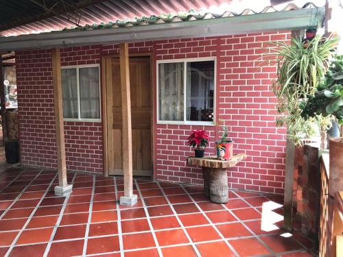 een rood bakstenen huis met een deur en een tafel bij Hospedaje rural - Finca la Aurora - Caqueza in Cáqueza