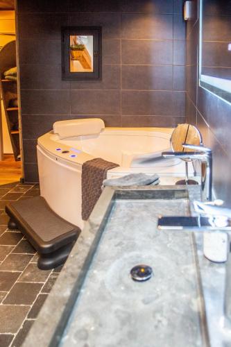 a bath tub in a bathroom with a sink at Een vleugje wellness in de Voerstreek - Bed & Brocante Onder de Poort in Voeren