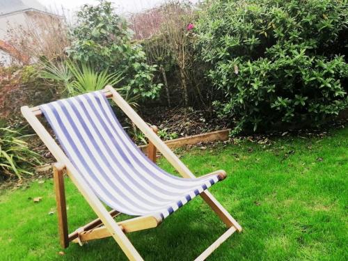 une chaise de plage assise sur l'herbe dans une cour dans l'établissement le chalet de laura, à Pornic