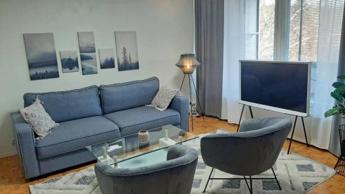 sala de estar con sofá azul, sillas y TV en Apartment Puijo & autotalli, en Kuopio