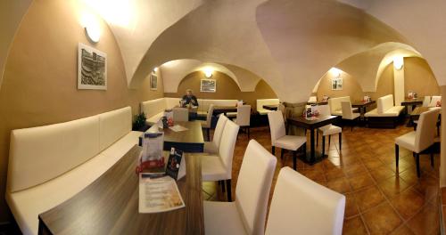 a restaurant with white chairs and a person sitting at a table at Fontana Pizzeria - Pension in České Budějovice