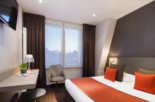 パリにあるアクロポールのベッド、デスク、窓が備わるホテルルームです。