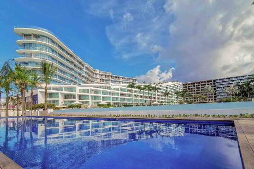 a large building with a swimming pool in front of it at Precioso Loft a pie de playa in Nuevo Vallarta