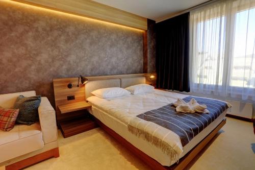 a bedroom with a large bed and a couch at Woodside Kopaonik 417-418 in Kopaonik