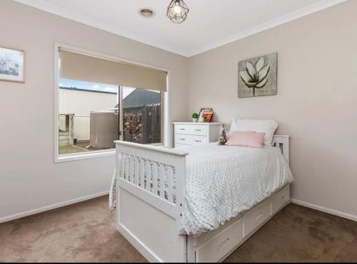 a white bedroom with a bed and a window at Modern family home with pool in Carisbrook