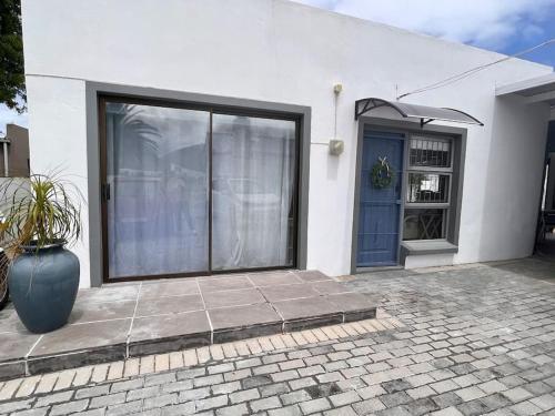 a white house with a blue door and a vase at Adorable 2 Bedroom Cottage with spacious veranda in Hermanus