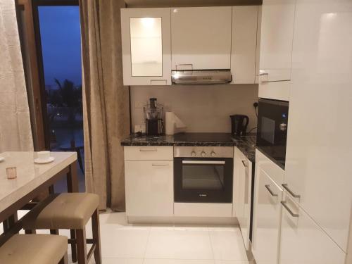 a kitchen with white appliances and a table and a window at Forest Island apartment in Salalah in Salalah