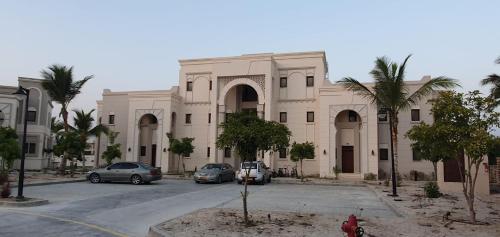 a large building with cars parked in front of it at Forest Island apartment in Salalah in Salalah