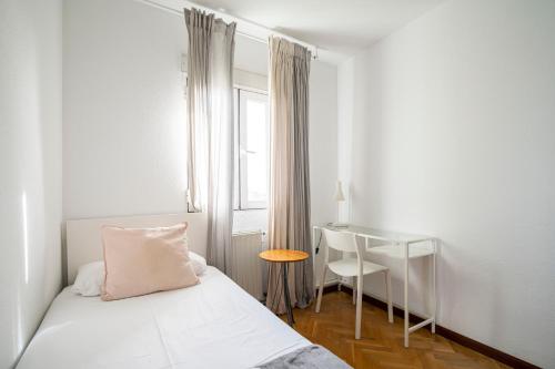 a bedroom with a bed and a table and a window at MODERN AND BRIGHT APARTMENT Plaza Elíptica -MAGIN in Madrid