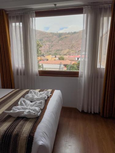a bedroom with a bed and a large window at Hotel Andes de Urubamba in Urubamba