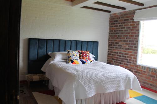 a bedroom with a bed and a brick wall at Villa La F in Guasca