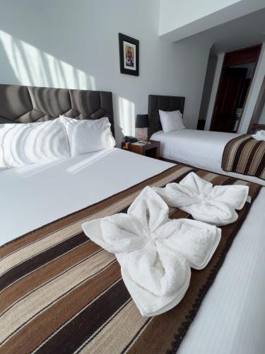 two beds with white towels on them in a room at Hotel Andes de Urubamba in Urubamba