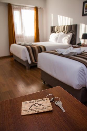 a hotel room with two beds and a table with keys at Hotel Andes de Urubamba in Urubamba