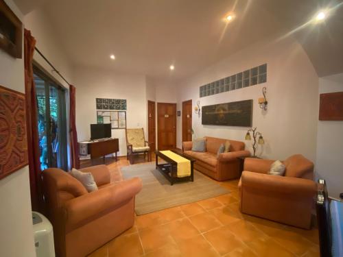 uma sala de estar com sofás e um piano em The Garden Apartment at The Hacienda em Boquete