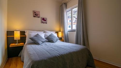 a bedroom with a bed with pillows and a window at Madeira Inn Vilamar in Calheta
