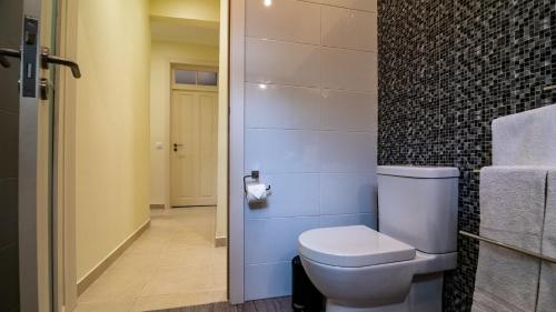 a bathroom with a toilet and a tile wall at Madeira Inn Vilamar in Calheta