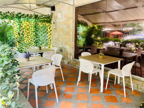 un restaurante con mesas y sillas y una pared de plantas en Hotel Palma 70, en Medellín