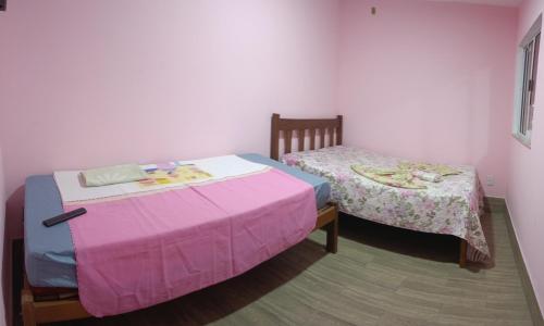 1 dormitorio con 2 camas con sábanas rosas en kitnet pé na areia reservado por sayonara, en Ilhéus