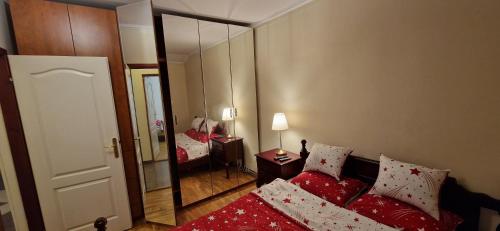 um quarto com uma cama vermelha e um espelho em Julija 3 em Pančevo