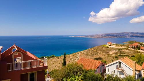 a view of the ocean from a hill with houses at Aeolos Studios Kefalonia in Khelmáta
