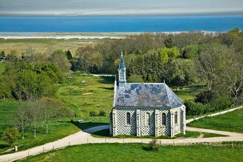 una vieja iglesia en un campo junto al océano en LE CLOS DE BEAUCHAMP APPARTEMENT Le BORD DE MER 2 vélos sont disponibles gratuitement, en Saint-Valery-sur-Somme