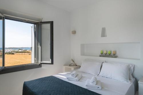 a white bedroom with a bed with towels on it at Blue diamonds villas Paros in Pounda