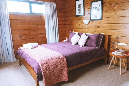 a bedroom with a bed with purple sheets and a window at Comfortable Cosy Retreat in Rotorua