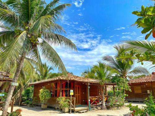 a house on the beach with palm trees at Hotel Camino Verde in Tolú