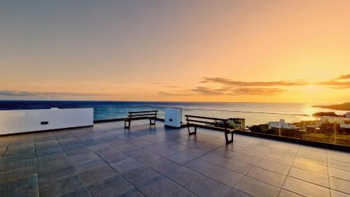 a balcony with two benches and a view of the ocean at Apartamento encantador com piscina e vista mar in Praia