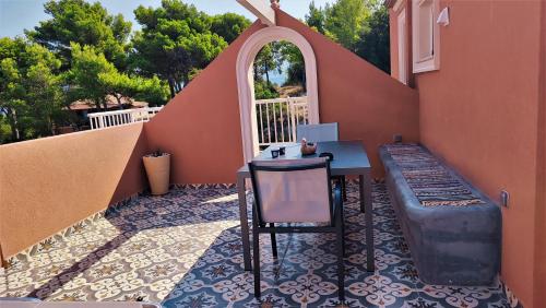 a patio with a table and a bench next to a building at Aeolos Studios Kefalonia in Khelmáta