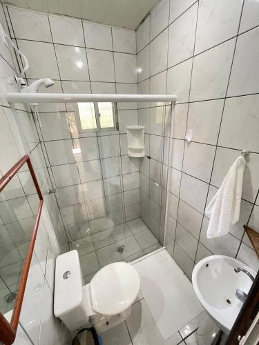 a white bathroom with a toilet and a sink at Moradas Dona Dalcema in Guarda do Embaú
