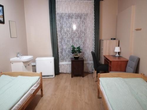 Zimmer mit 2 Betten, einem Waschbecken und einem Schreibtisch in der Unterkunft Hostel Gliwice Centrum in Gliwice