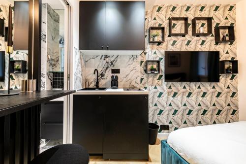 - une cuisine avec évier et une télévision dans la chambre dans l'établissement Le Studio Du Parc Monceau, à Paris