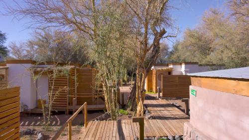 a house with a wooden deck and some trees at Lodge Quelana in San Pedro de Atacama