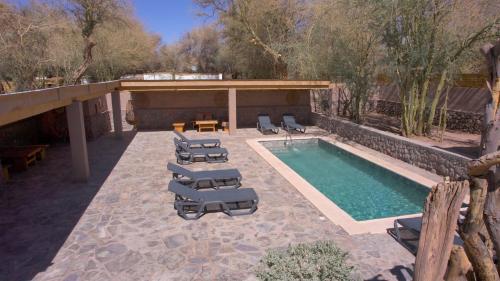 a swimming pool with chaise lounge chairs and a table and a pool at Lodge Quelana in San Pedro de Atacama