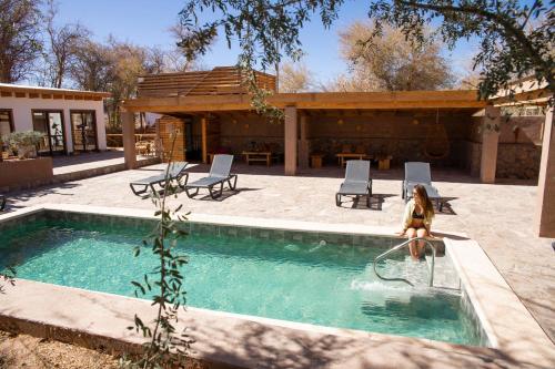 una mujer está sentada en una piscina en Lodge Quelana en San Pedro de Atacama
