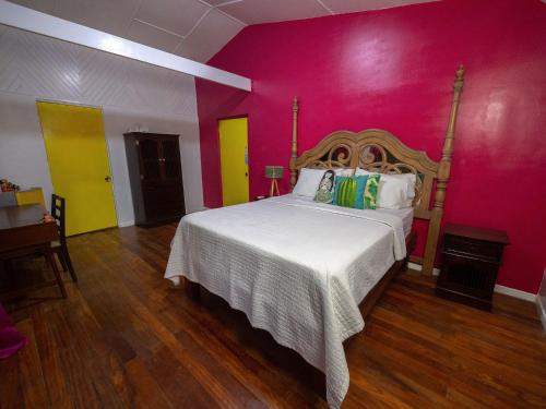 a bedroom with a bed in a pink wall at El Reinas by Sugar's Monkey in Playa Grande