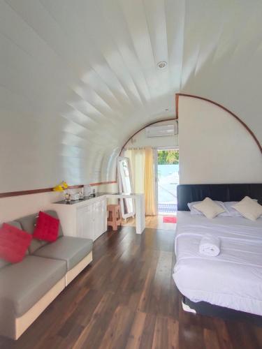 1 dormitorio con 1 cama y 1 sofá en una habitación en Mercy Cottage, en Langgur