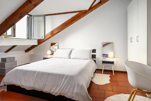 sypialnia z białym łóżkiem i krzesłem w obiekcie [Duomo - Pt.Romana - Bocconi] Top Floor Apartment w Mediolanie