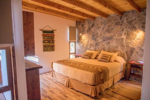 a bedroom with a bed with a stone wall at Lodge Quelana in San Pedro de Atacama