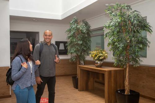 a man and a woman standing next to two potted trees at Casa Andina Standard Cusco Catedral in Cusco