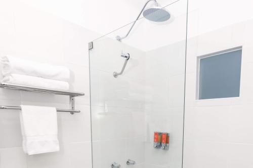 a white bathroom with a shower and a sink at Casa Andina Standard Cusco Catedral in Cusco