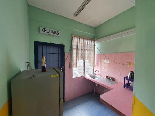 een keuken met een koelkast en een wastafel bij Deummah Guest Room in Cukai