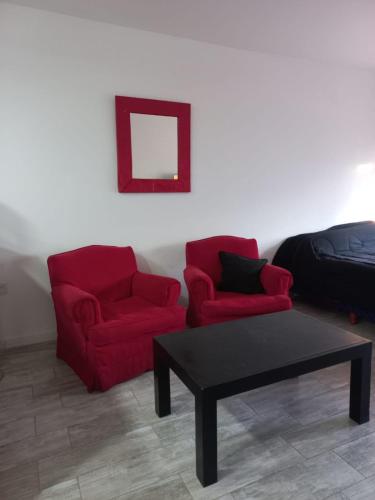 una sala de estar con 2 sillas rojas y una mesa. en Mexico's Depto en Buenos Aires