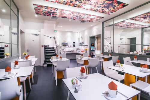 un restaurant avec des tables et des chaises blanches dans l'établissement Hotel Opéra Opal, à Paris