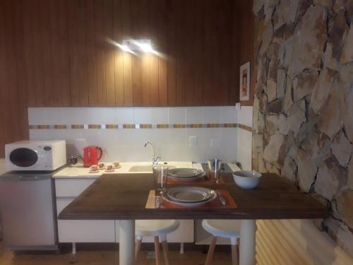 cocina con mesa de madera y pared de piedra en OLIVIAS LOFTS en Ushuaia