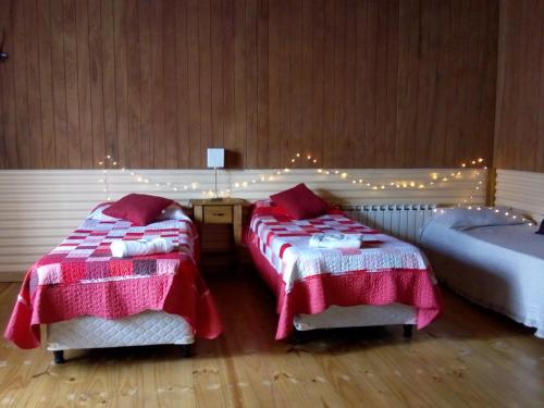 1 dormitorio con 2 camas con sábanas rojas y blancas en OLIVIAS LOFTS en Ushuaia