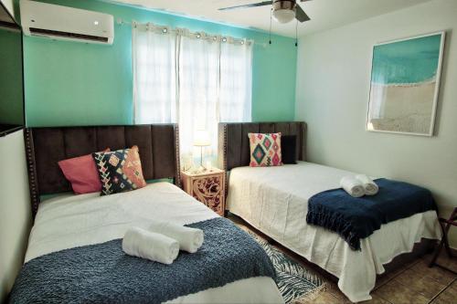 a bedroom with two beds and a window with a fan at Salinas House - The World’s favorite stay! in Salinas